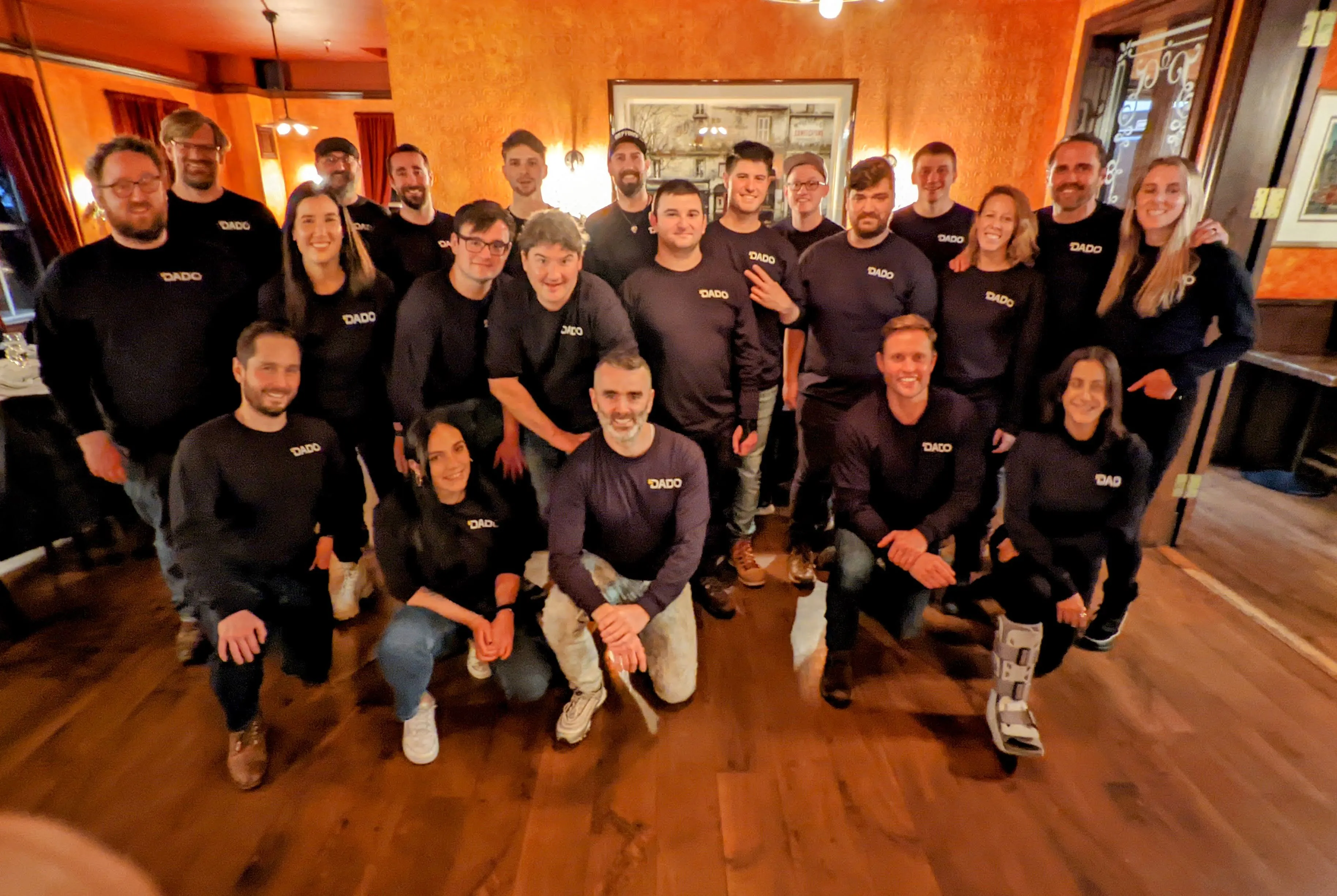 Full DADO team of approximately 20 people in matching company shirts with Gene front and center