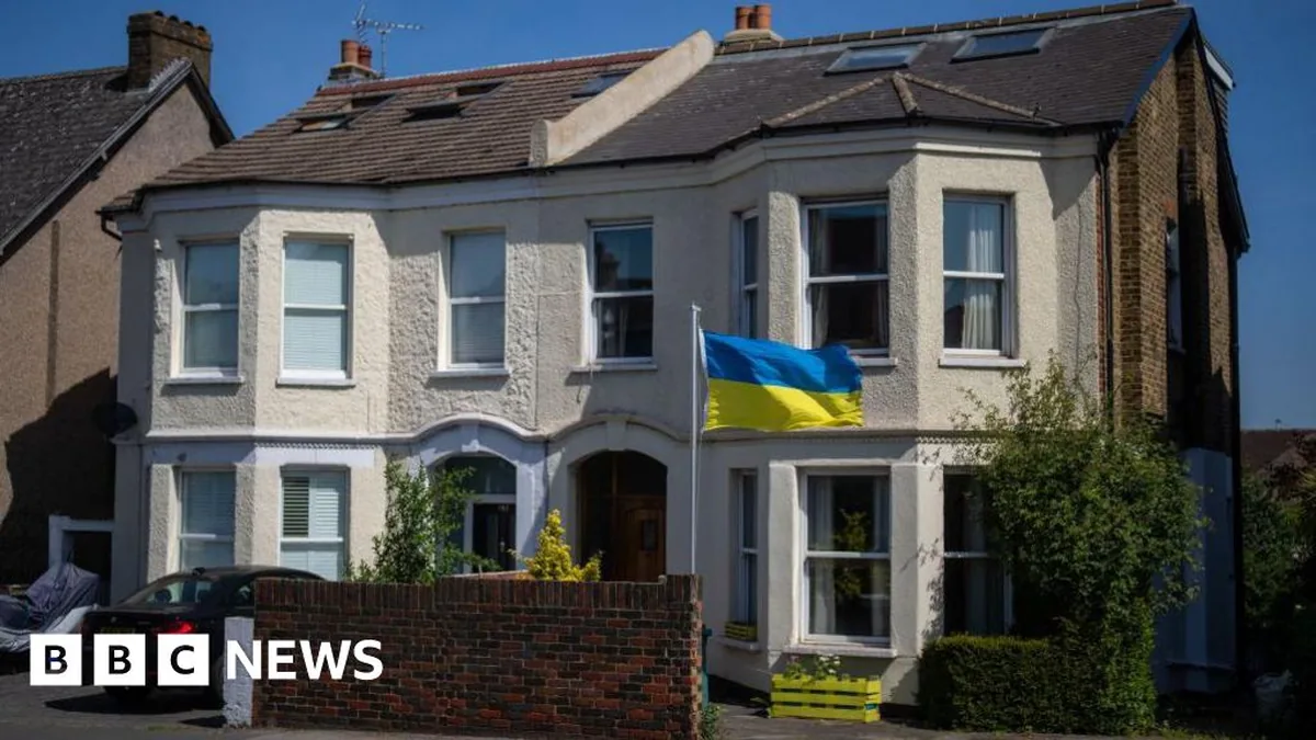 A semidetached victorian house. In the front garden a yellow and blue ukrainian flag has been erected. A window box has also been painted yellow.