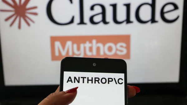 A smartphone displaying the Anthropic logo is shown in the foreground with a blurred Claude Mythos themed background. The image illustrates the branding of the artificial intelligence company in a technology themed visual composition.